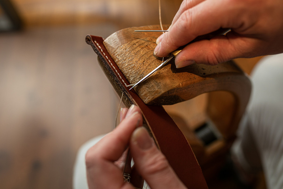 Artisan maroquinier Femme en train de coudre une ceinture en cuir